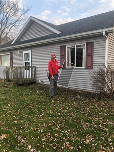 window cleaner holding a window screen of a window at a house