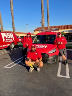 three window cleaners gathered around a red fish window cleaning van