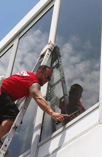 window cleaner cleaning windows of a building while on a ladder