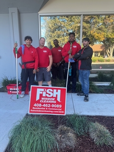 four window cleaners standing behind a fish sign and in front of a building