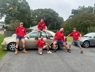 five fish window cleaning employees standing in front and sitting on top of a beige car