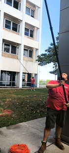 two window cleaners using poles to clean windows of a building